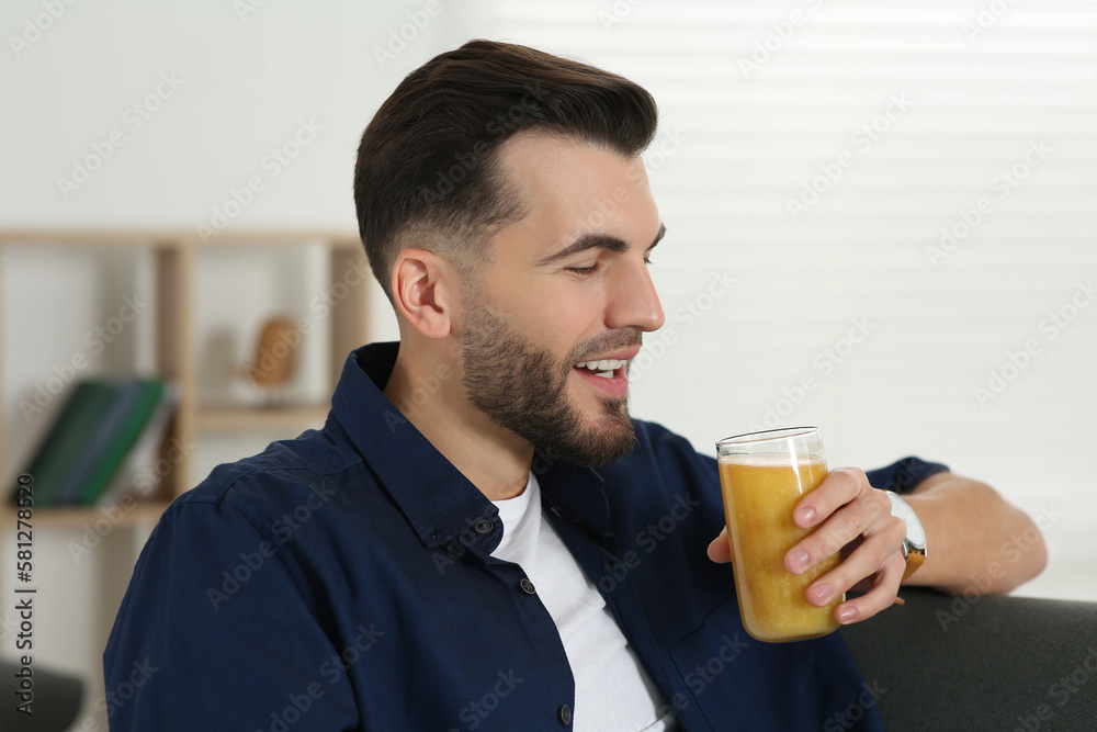 Handsome man with delicious smoothie on sofa at home Handsome man with delicious smoothie on sofa at home