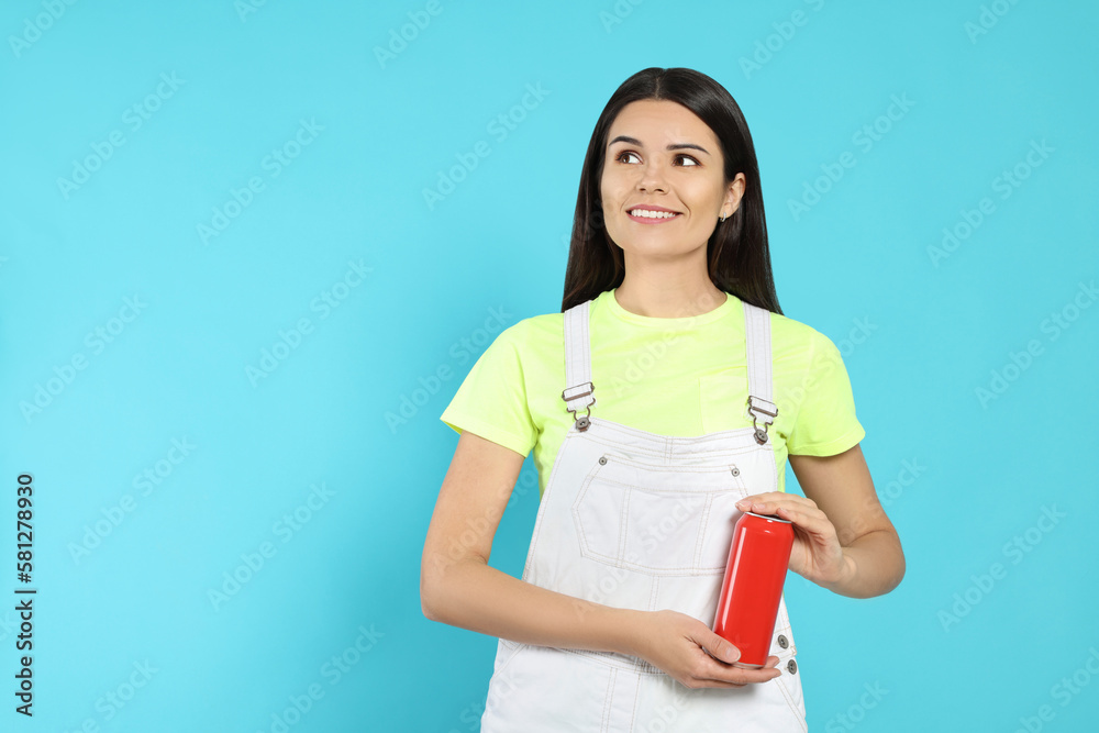 Beautiful happy woman holding red beverage can on light blue background. Space for text Beautiful happy woman holding red beverage can on light blue background. Space for text