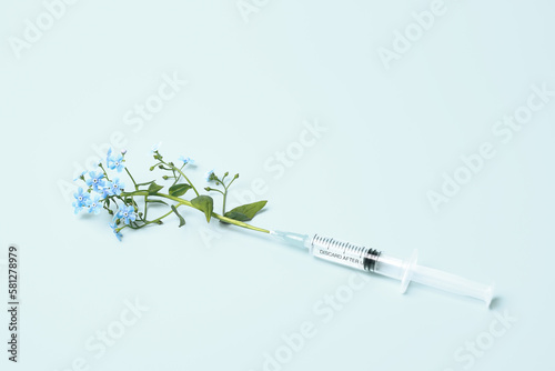 Syringe and flowers on blue background, beauty injections creative concept