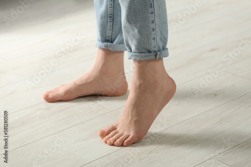 Woman stepping barefoot in room at home, closeup. Floor heating