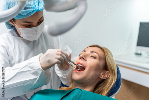 Female dentist examine tooth to Caucasian girl at dental health clinic. 