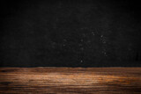 Wooden table on black wall in dark room background