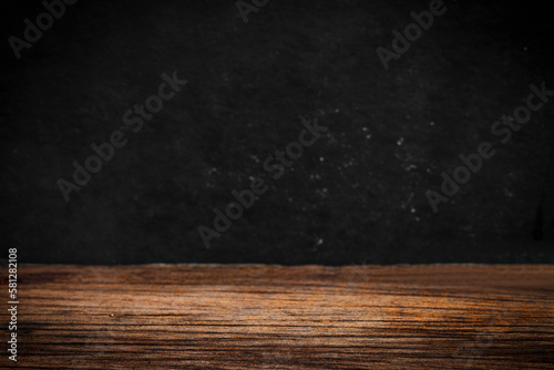 Wooden table on black wall in dark room background