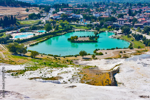 Travertine terrace near hot springs against town. Turquoise water travertine pools at pamukkale