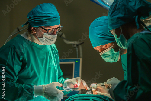 Fototapeta Naklejka Na Ścianę i Meble -  Team of surgery doctor in Operating Room, Assistant Hands out Instruments to Surgeons During Operation. doctor and nurse surgeons in green gown coat at hospital operating theater.