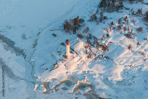 Snowy aerial drone view of Povorotny lighthouse, Vikhrevoi island, Gulf of Finland, Vyborg bay, Leningrad oblast, Russia, winter sunny day with a blue sky, lighthouses of Russia travel photo