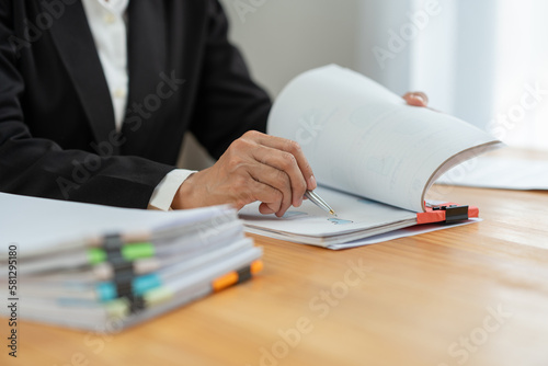 Financial advisor, analyst, asian businesswoman pointing at financial statistics report paper business income Taxes piled up on the desk to validate presentations at office meetings.