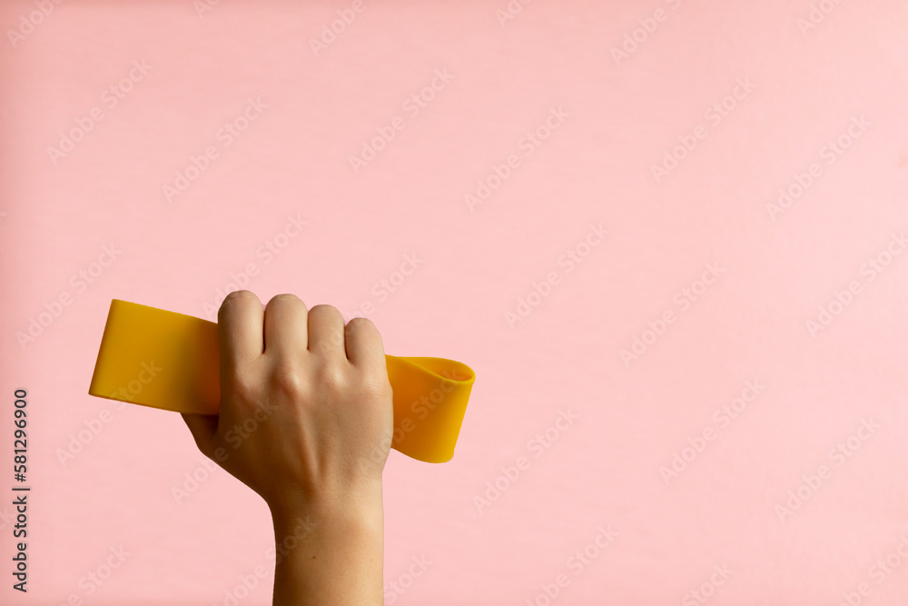 Womans hand with yellow sports tape on pink background Womans hand with yellow sports tape on pink background