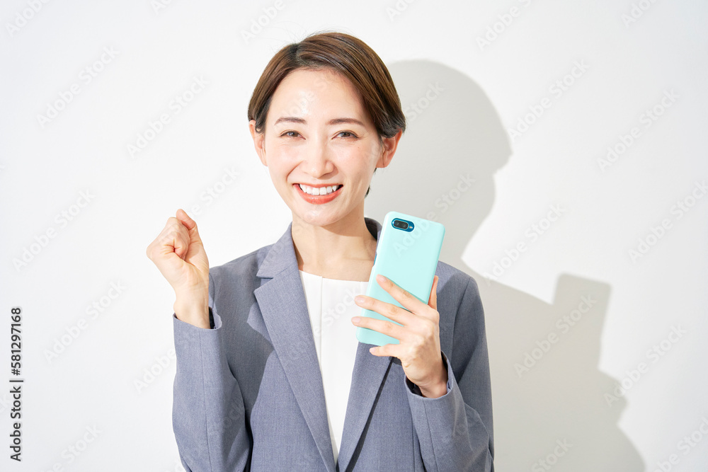 スマートフォンを持ってガッツポーズをするビジネスウーマン 白背景 スマートフォンを持ってガッツポーズをするビジネスウーマン 白背景