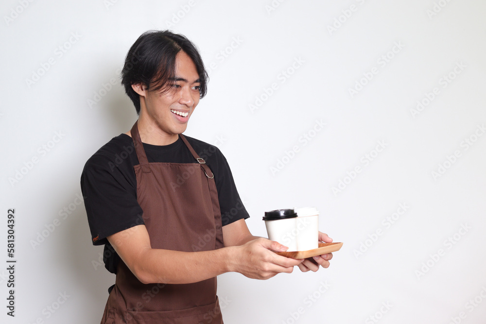 Portrait of attractive Asian barista man in brown apron holding two take away paper coffee cups. Isolated image on white background Portrait of attractive Asian barista man in brown apron holding two take away paper coffee cups. Isolated image on white background