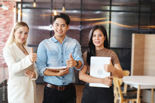 Portrait of smiling happy multiethnic teamwork thumbs up in the office. Encourage your team to continue to succeed. Satisfaction business concept © Wannachai