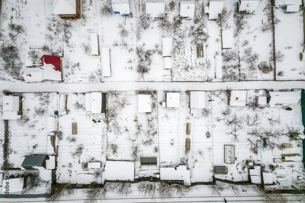 Aerial view of coniferous winter forest and a small houses.. Flying above frozen trees and snow covered ground of dense forest and a small houses for glamping. Aerial view of coniferous winter forest and a small houses.. Flying above frozen trees and snow covered ground of dense forest and a small houses for glamping.