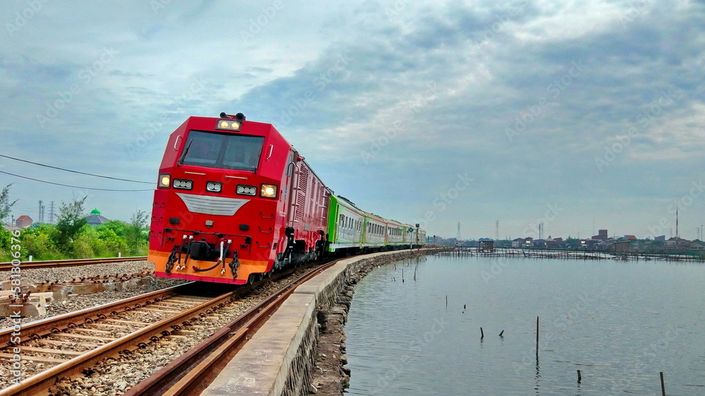 Special Train with Red Locomotive Runs on The Side of The Lake at Semarang City