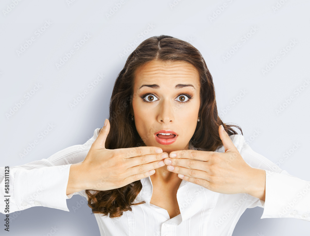 Unbelievable news! Excited surprised, shocked businesswoman, indoors. Business woman covering open mouth with hands, isolated on grey gray background.