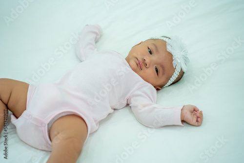 Smiling Cute baby girl lying on a bed sleeping on white sheets