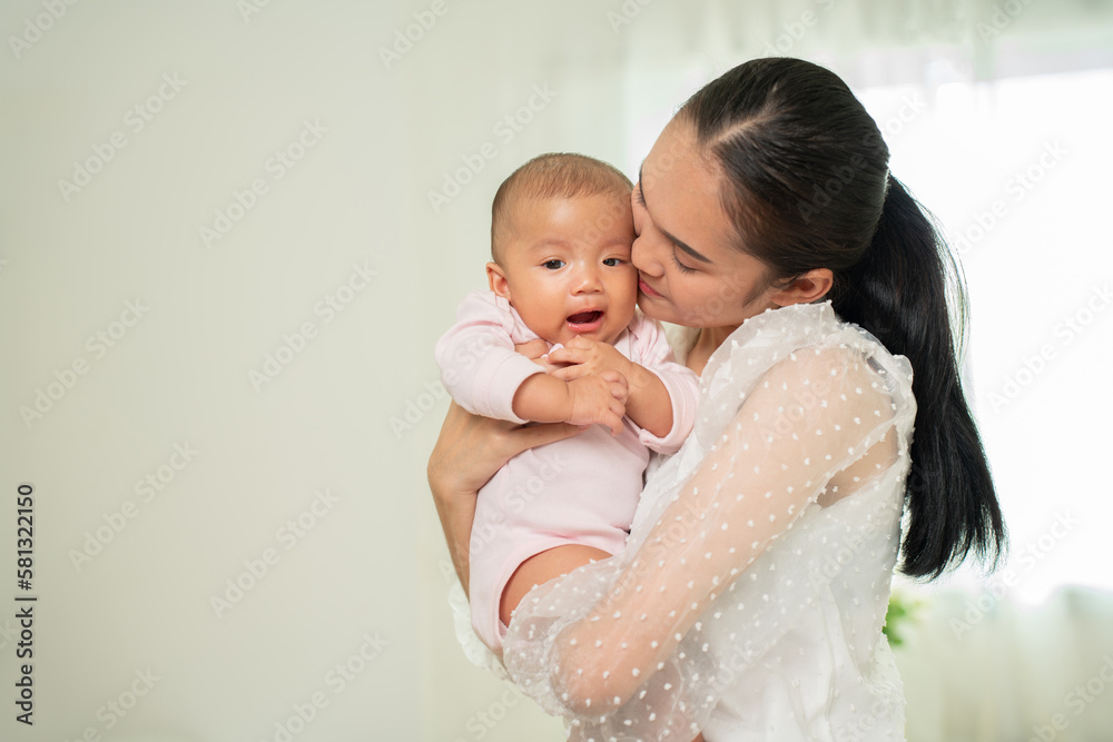 Loving Asian Mom carying of her newborn baby at home in the bedroom. happy family. mother playing with her baby in the bedroom. Mother hugging her little 2 months old Girl. Loving Asian Mom carying of her newborn baby at home in the bedroom. happy family. mother playing with her baby in the bedroom. Mother hugging her little 2 months old Girl.