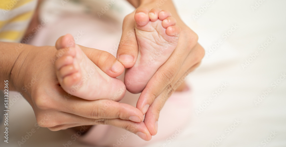 Asian Mother hands in heart shape. Baby feet in mother's hands that mean symblo of love. Mom and her Baby Child. Happy Family concept. Beautiful conceptual image of Mother and newborn baby family
