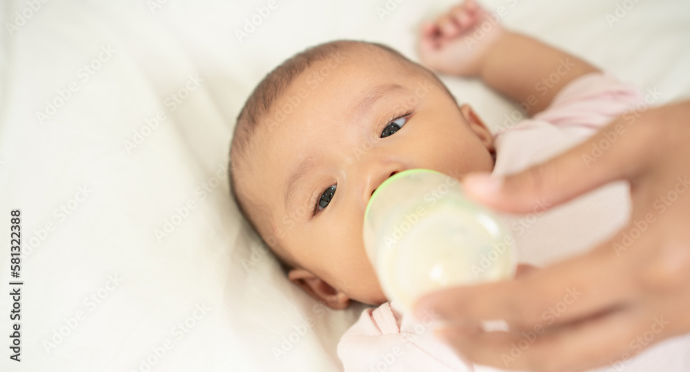 Asian mother feeds her baby from bottle's Milk. Newborn Baby Drinking Milk. Asian mother feeds her baby from bottle's Milk. Newborn Baby Drinking Milk.