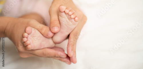 Asian Mother hands in heart shape. Baby feet in mother's hands that mean symblo of love. Mom and her Baby Child. Happy Family concept. Beautiful conceptual image of Mother and newborn baby family