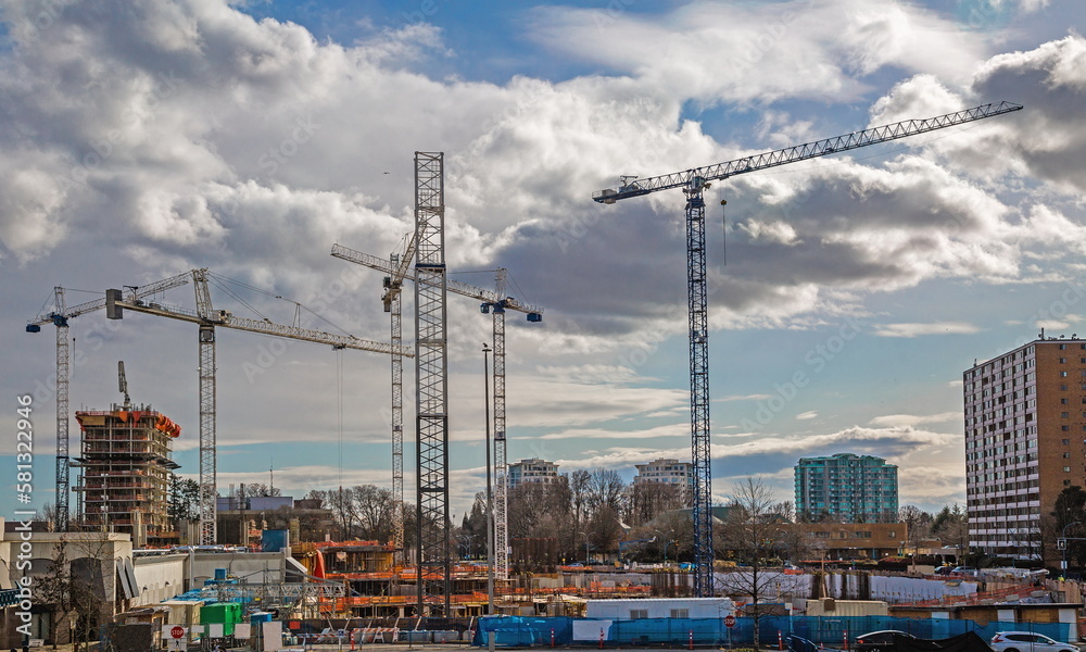 Large construction site in Richmond City with construction cranes working on a construction complex where foundations are laid and construction of floors of high-rise buildings has begun