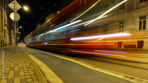 Red tram in motion long exposure passing by night city with old buildings