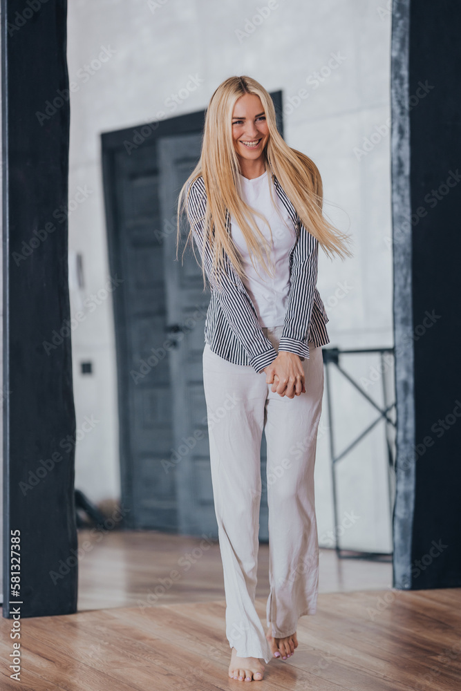 Vertical shoot of blonde Swedish girl in casual laughing comes in new apartment with fluttering hair, happy purchased home. Adorable shy caucasian young woman enjoying weekend. Smile. Romance, love.