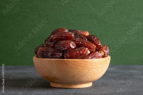 Date fruits in wooden bowl,on green background  photo