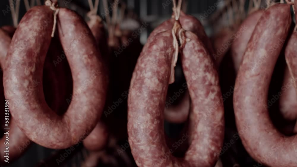 Close-up of the production technology of sausage and smoked meat. Meat delicacies on the metal frame. Appetizing smoked. Meat Factory. Rows of ham, salami