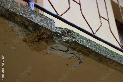 Damaged balcony on a old house in Italy. Balcony with cracked concrete. Balcony repair, cracks in reinforced concrete structure photo