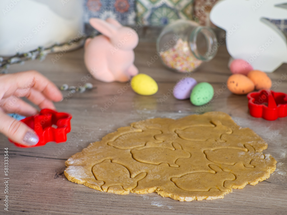Womens hands close-up kneading ginger dough and carving figurines from it. The shapes of rabbit. Cutting sugar cookie dough with Easter shaped cookie cutters. Preparation for Easter. Holidays baking.