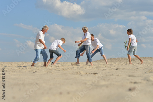 Family playing football on a beach in summer day