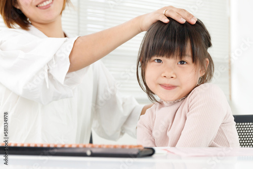 学習塾や家庭学習で褒められてうれしい子供。頭を撫でられている女の子 © hikari_stock