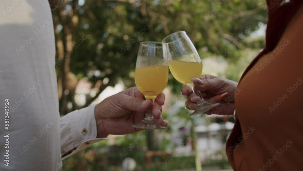 An adult couple celebrates with two cocktail glasses outside in nature. An adult couple celebrates with two cocktail glasses outside in nature.