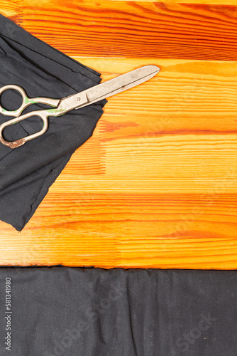 Tailoring Concepts. Old Metal Rusty Scissors Placed Together with Black Fabrics on wooden Surface photo