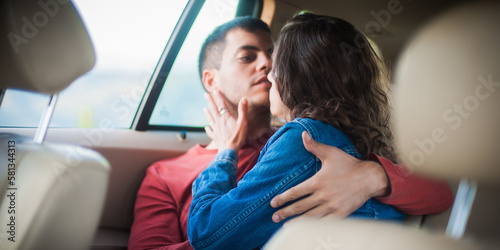Passionate kiss in car. Young sexy couple in love, sitting in the back seat, looking and kissing passionately each other, just before sex. Desire, passion and love concept