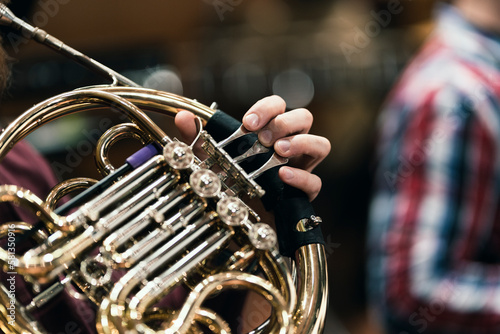A French horn player playing their instrument during a wind ensemble rehearsal