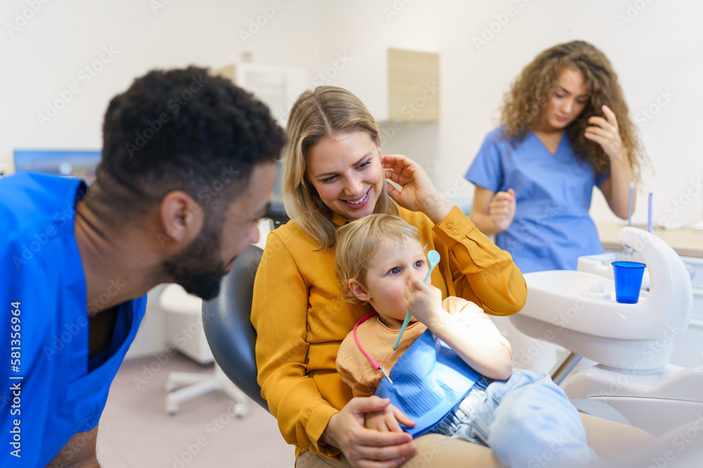 Young mother with her little daughter sitting at dentist chair, in his office. Young mother with her little daughter sitting at dentist chair, in his office.
