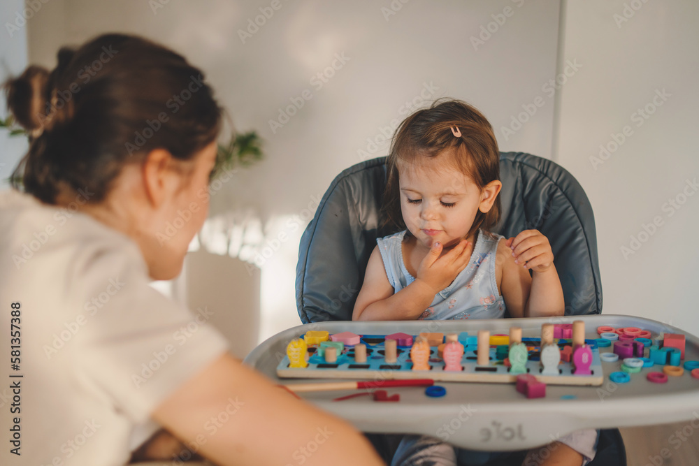 Happy caucasian baby girl sitting on high chair and playing with