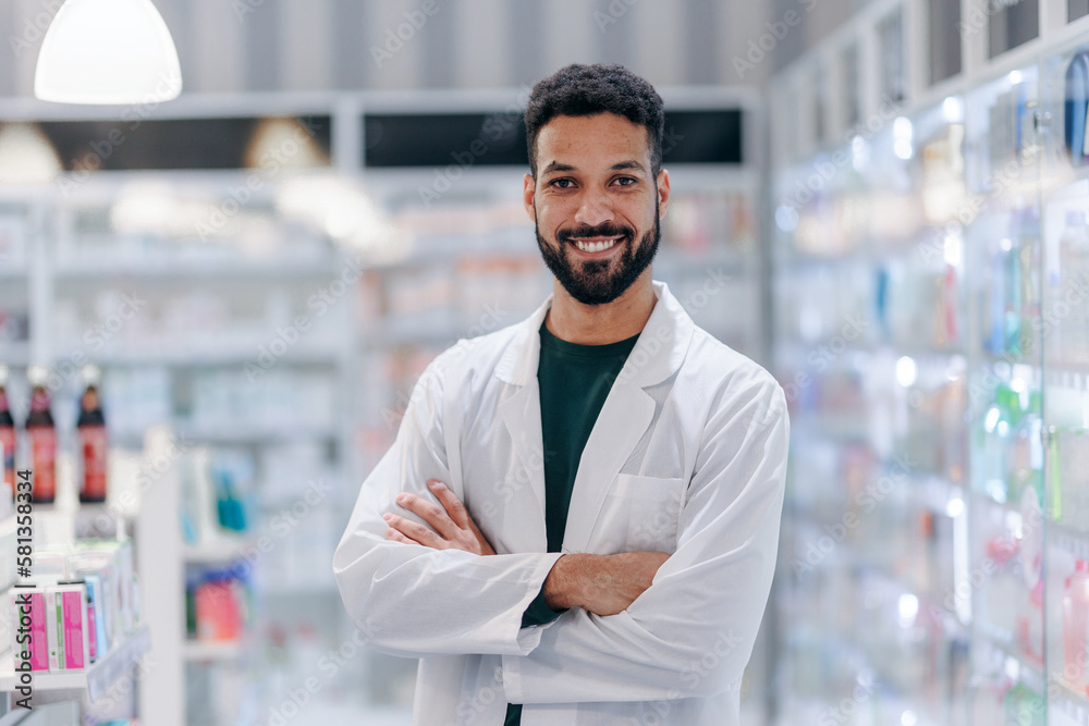 Fototapeta premium Portrait of young multiracial pharmacist looking at camera, standing in a pharmacy shop.