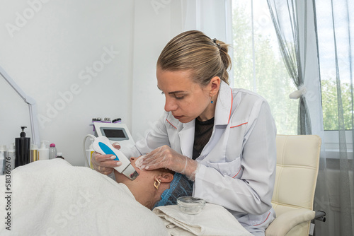 young attractive woman receiving an ultrasonic cleaning of her facial skin by a professional