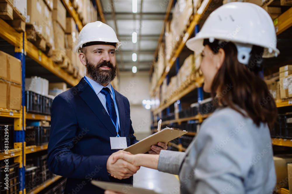 Managers in suits shaking hands in warehouse. Managers in suits shaking hands in warehouse.