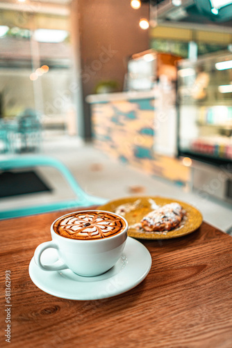 Cappuccino coffee in white mug with pastry dessert in a specialty coffee shop with natural light