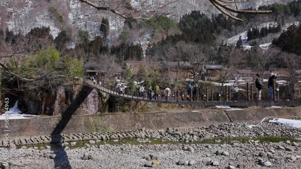 People Crossing Bridge over River to Shirakawa-Go in the Mountains of Gifu Japan