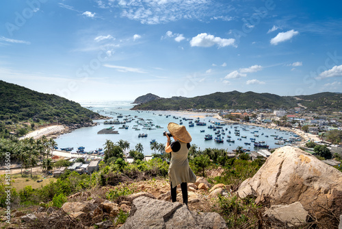 Female tourist takes photos of the boats anchored in a fishing village, a great vacation when traveling to Vietnam in summer or spring