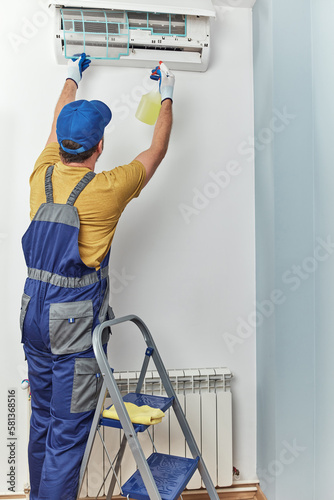 Repairman cleaning and fixing indoors AC unit.