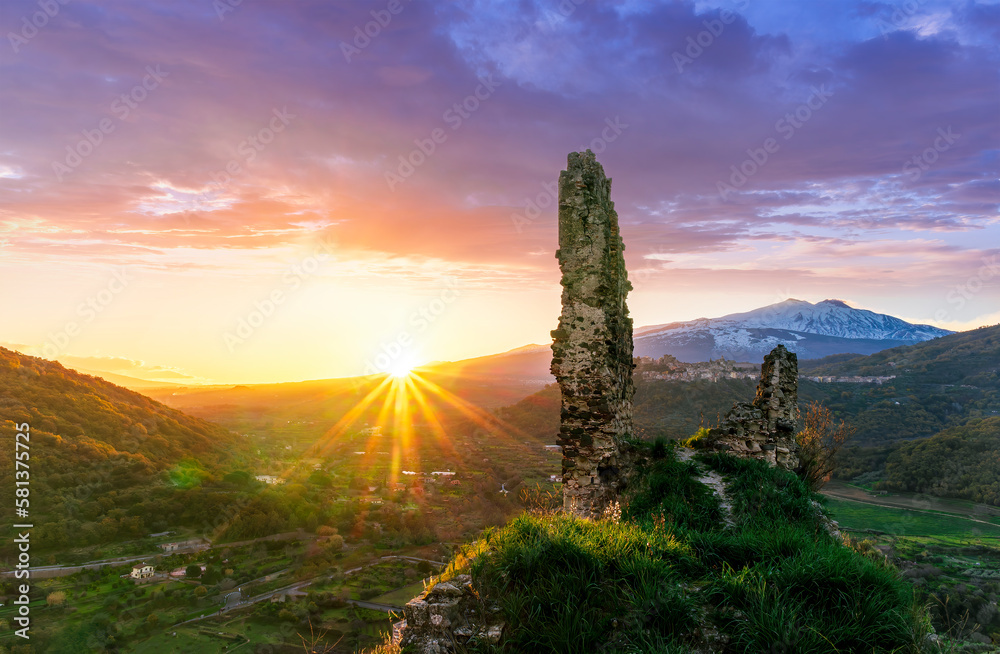 beautiful sunset or sunrise landscape of ancient ruins on a top of a hill with green mountains with white snow top on background