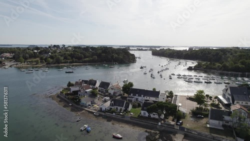 Homes on Island of Conleau in Vannes Northern France with boat navigating La Marle water passage, Aerial flyover shot photo