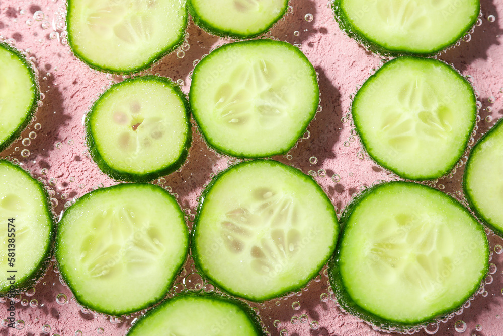 Slices of cucumber in water on pink background Slices of cucumber in water on pink background