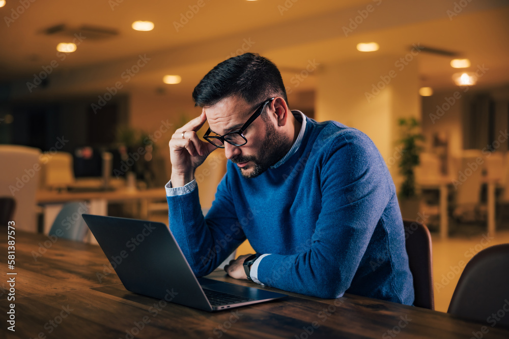 Thoughtful man working over the laptop, sitting at the workplace.