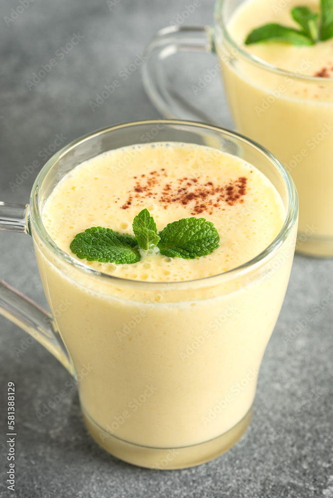 Lassi mango close-up. Traditional Indian drink, gray background. Refreshing milkshake. Side view, selective focus Lassi mango close-up. Traditional Indian drink, gray background. Refreshing milkshake. Side view, selective focus